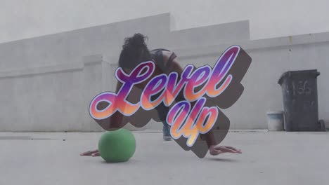 Animation-of-level-up-text-over-mixed-race-woman-doing-push-ups-on-a-ball