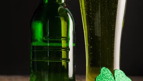 Animation-of-bottle-and-glass-of-beer-clover-leaf-on-wooden-table