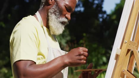 Älterer-Afroamerikanischer-Mann-Malt-Bild-Auf-Einer-Leinwand-Im-Sonnigen-Garten