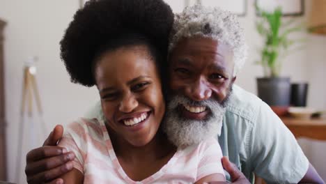 Porträt-Eines-Glücklichen-Afroamerikanischen-Paares,-Das-Auf-Der-Couch-Sitzt-Und-Sich-Umarmt-Und-In-Die-Kamera-Lächelt