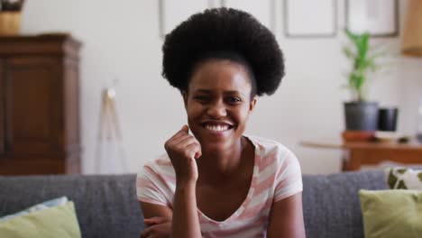 Porträt-Einer-Glücklichen-Afroamerikanischen-Frau,-Die-Auf-Der-Couch-Sitzt-Und-In-Die-Kamera-Lächelt