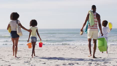 Afroamerikanische-Eltern-Und-Ihre-Kinder-Halten-Strandausrüstung-Am-Strand