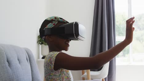 Afroamerikanisches-Mädchen-Gestikuliert,-Während-Sie-Zu-Hause-Auf-Der-Couch-Sitzt-Und-Ein-VR-Headset-Verwendet