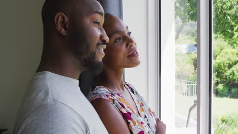 Afroamerikanisches-Paar-Redet-Miteinander,-Während-Es-Zu-Hause-Aus-Dem-Fenster-Schaut