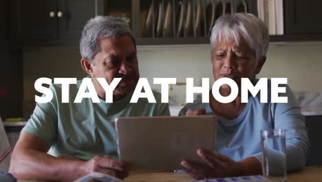 Stay-at-home-text-against-african-american-senior-couple-suing-digital-tablet-at-home