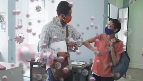 Animation-of-covid-19-cells-over-man-and-woman-touching-elbows-in-office-wearing-face-masks