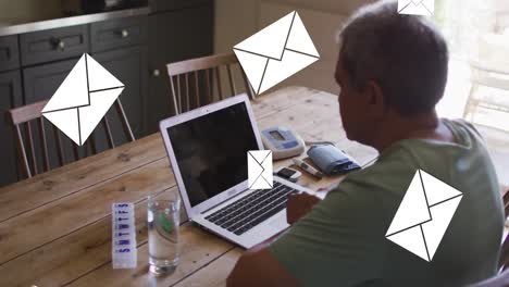 Animation-of-envelope-icons-over-senior-man-using-laptop-at-home-in-background