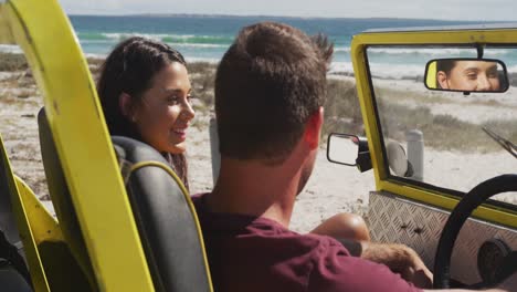 Happy-caucasian-couple-sitting-in-beach-buggy-by-the-sea-talking