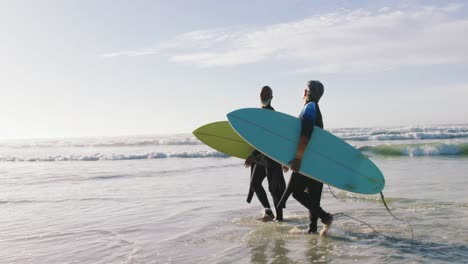 Senior-african-american-couple-walking-with-surfboards-at-the-beach