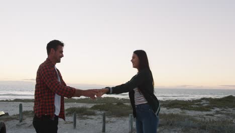 Happy-caucasian-couple-dancing-on-the-beach-by-the-sea