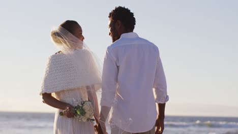 Verliebtes-Afroamerikanisches-Paar-Heiratet,-Schaut-Sich-An-Und-Hält-Händchen-Am-Strand