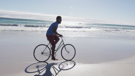 Hombre-Afroamericano-Sonriendo-Y-Andando-En-Bicicleta-En-La-Playa