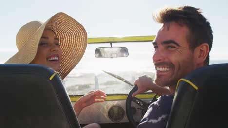 Happy-caucasian-couple-sitting-in-beach-buggy-by-the-sea-talking