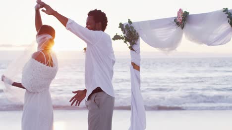 Afroamerikanisches-Verliebtes-Paar-Heiratet,-Lächelt-Und-Tanzt-Am-Strand-Bei-Sonnenuntergang