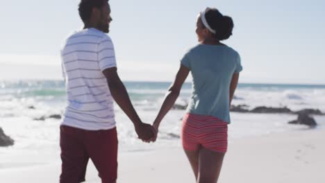 Afroamerikanisches-Paar-Lächelt,-Hält-Händchen-Und-Geht-Am-Strand-Spazieren