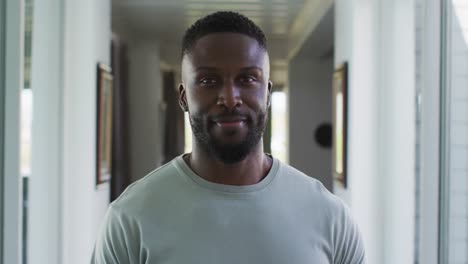 Portrait-of-african-american-man-smiling-while-standing-at-home