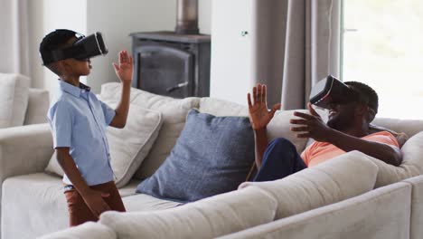 Afroamerikanischer-Vater-Und-Sohn-Nutzen-Gemeinsam-VR-Headsets-Auf-Einer-Couch