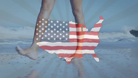Die-Amerikanische-Flagge-Weht-über-Der-Landkarte-Vor-Dem-Unteren-Teil-Einer-Frau,-Die-Am-Strand-Spaziert
