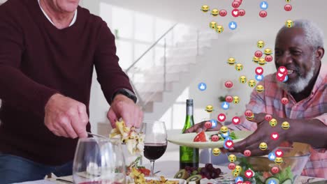 Multiple-face-emojis-floating-against-two-diverse-senior-men-having-food-at-home