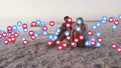 Multiple-heart-and-like-icons-floating-against-caucasian-couple-drinking-beer-on-the-beach