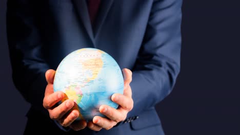 Midsection-of-businessman-holding-glowing-globe-in-his-hands-on-grey-background