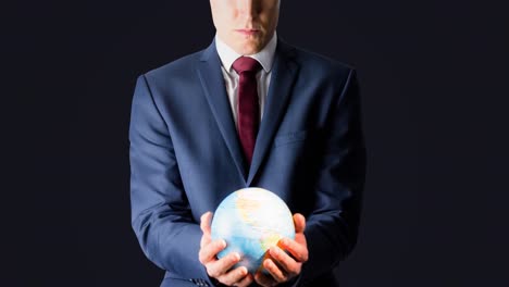 Businessman-holding-glowing-globe-in-his-hands-on-grey-background