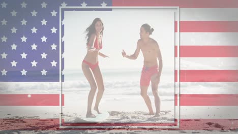Animation-of-american-flag-waving-over-man-and-woman-learning-to-surf-on-beach