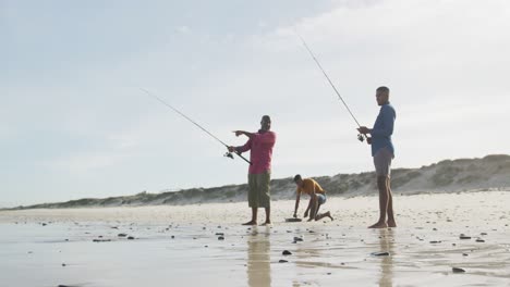 African-american-senior-father-and-two-teenage-sons-standing-on-a-beach-fishing-and-talking