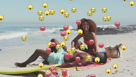 Animation-of-social-media-emojis-over-smiling-couple-on-beach