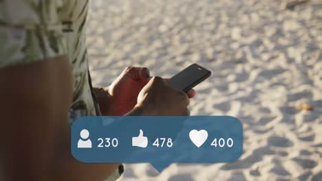 Animation-of-people,-thumbs-up-and-heart-icons-with-numbers-over-man-using-smartphone-on-beach