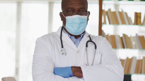 Médico-Senior-Afroamericano-Vestido-De-Blanco-Cruzando-Los-Brazos-Mirando-A-La-Cámara