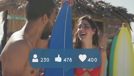 Animation-of-people,-thumbs-up-and-heart-icons-with-numbers-over-friends-with-surfboards-on-beach