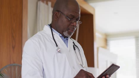 African-american-senior-male-doctor-wearing-white-coat-writing-in-notebook