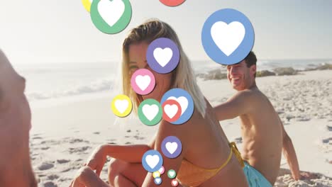 Animation-of-heart-digital-icons-over-friends-having-fun-on-beach