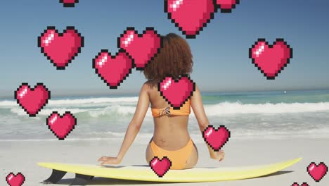 Animation-Digitaler-Herzsymbole-über-Einer-Frau,-Die-Auf-Einem-Surfbrett-Am-Strand-Sitzt