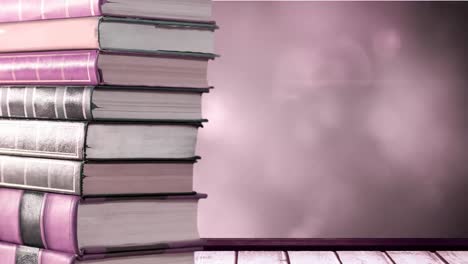 Animation-of-stack-of-books-with-copy-space-over-glowing-pink-lights