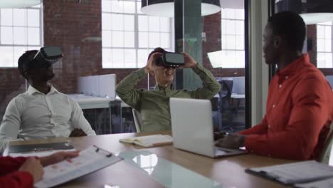 Diverse-group-of-business-colleagues-sitting-in-meeting-room-using-vr-headset