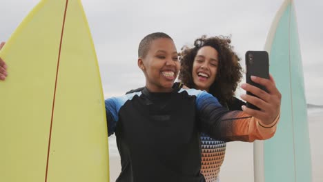 Fröhliche-Afroamerikanische-Freundinnen-Am-Strand-Mit-Surfbrettern,-Die-Ein-Selfie-Machen