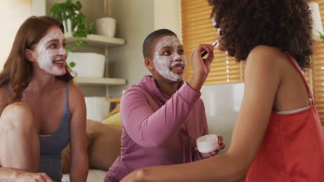 Diverse-group-of-happy-female-friends-trying-makeup-and-talking-at-home