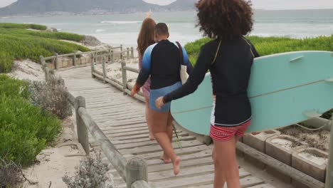 Eine-Vielfältige-Gruppe-Glücklicher-Freundinnen-Geht-Mit-Surfbrettern-An-Den-Strand