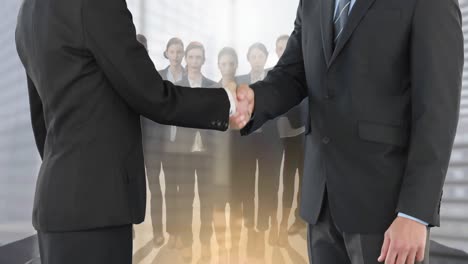 Animation-of-businessman-and-businesswoman-shaking-hands-over-group-of-businesspeople
