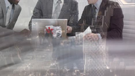 Mid-section-of-business-people-discussing-over-laptop-at-office-against-cityscape-in-background