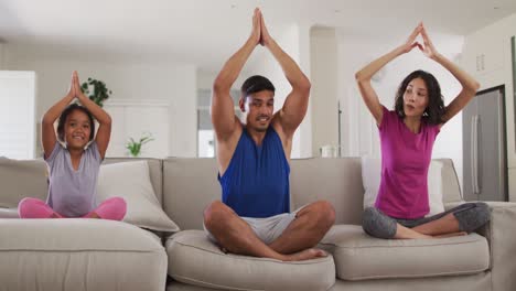 Hispanic-parents-and-daughter-sitting-on-the-sofa-meditating-at-home