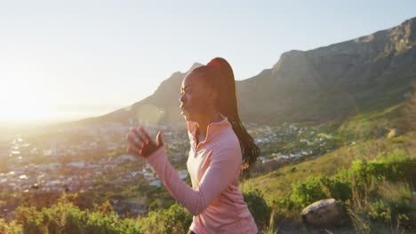 African-american-woman-exercising-outdoors-running-in-country-side-during-sunset