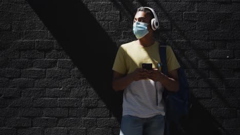 Mann-Mit-Gemischter-Rasse-Trägt-Gesichtsmaske-Und-Benutzt-Smartphone-Auf-Der-Straße