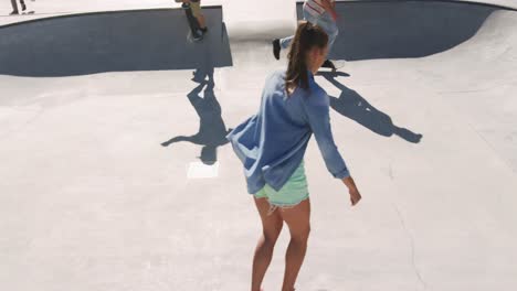 Caucasian-woman-and-two-male-friends-skateboarding-on-sunny-day