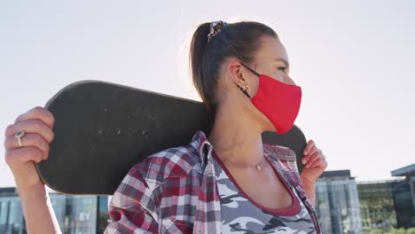Kaukasische-Frau-Mit-Gesichtsmaske-Und-Skateboards-An-Einem-Sonnigen-Tag