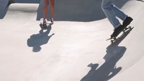 Low-section-of-caucasian-woman-and-two-male-friends-skateboarding-on-sunny-day