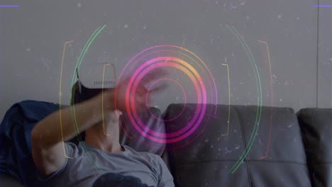 Light-trails-and-scope-scanning-over-caucasian-man-gesturing-while-wearing-vr-headset-at-home