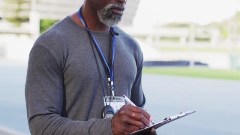 Mittelteil-Eines-Afroamerikanischen-Männlichen-Trainers,-Der-Sich-An-Einem-Sonnigen-Tag-Notizen-Macht